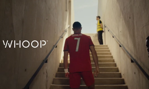Cristiano Ronaldo in his Portugal football jersey climbing stairs and the WHOOP logo to the left.