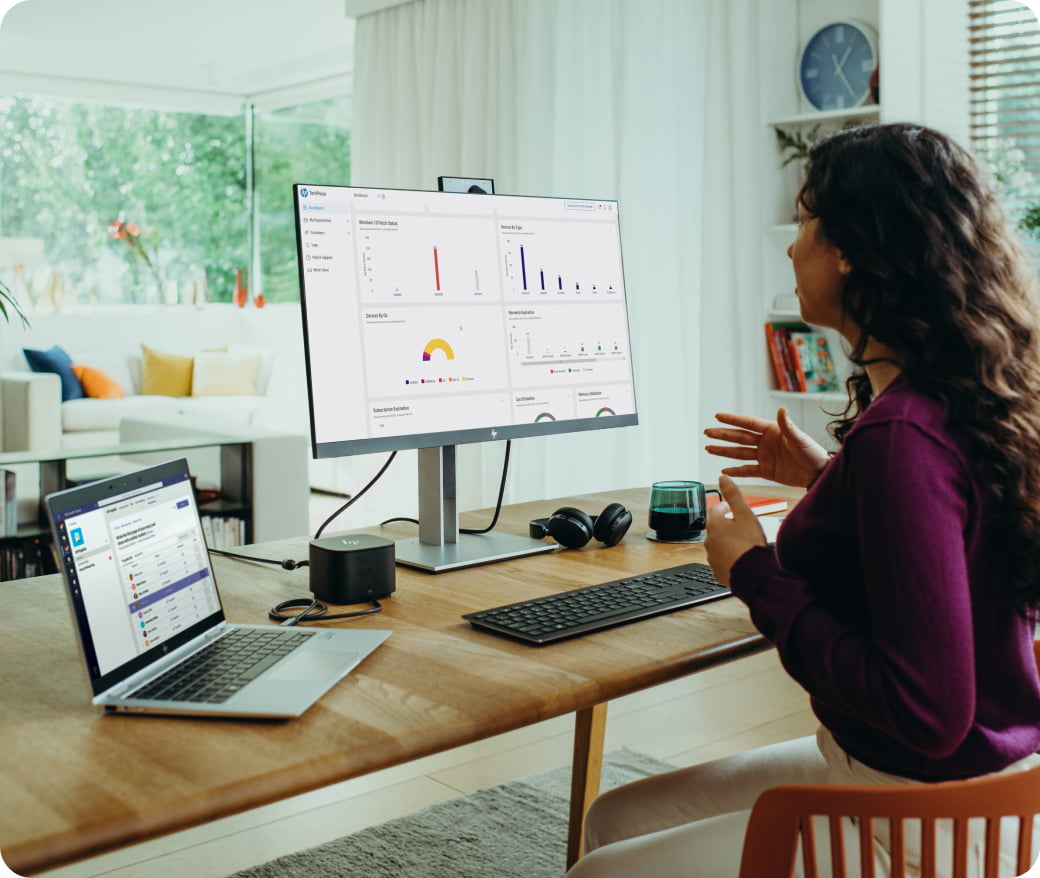 Woman working at home office desk with laptop and monitor