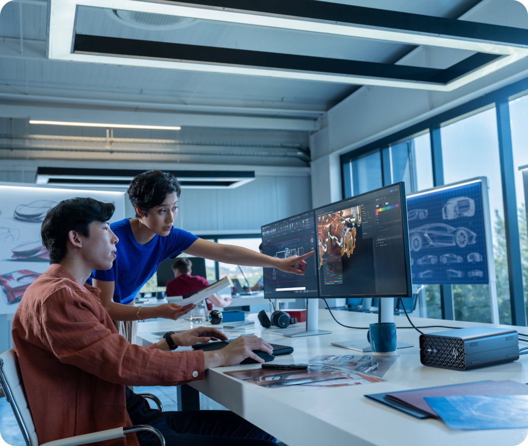 Man & woman in office looking at two monitors