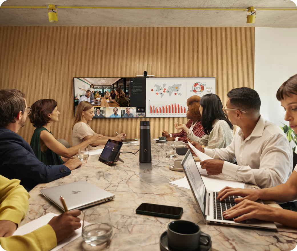 Conference room with employees connecting remotely to colleagues on large screens.
